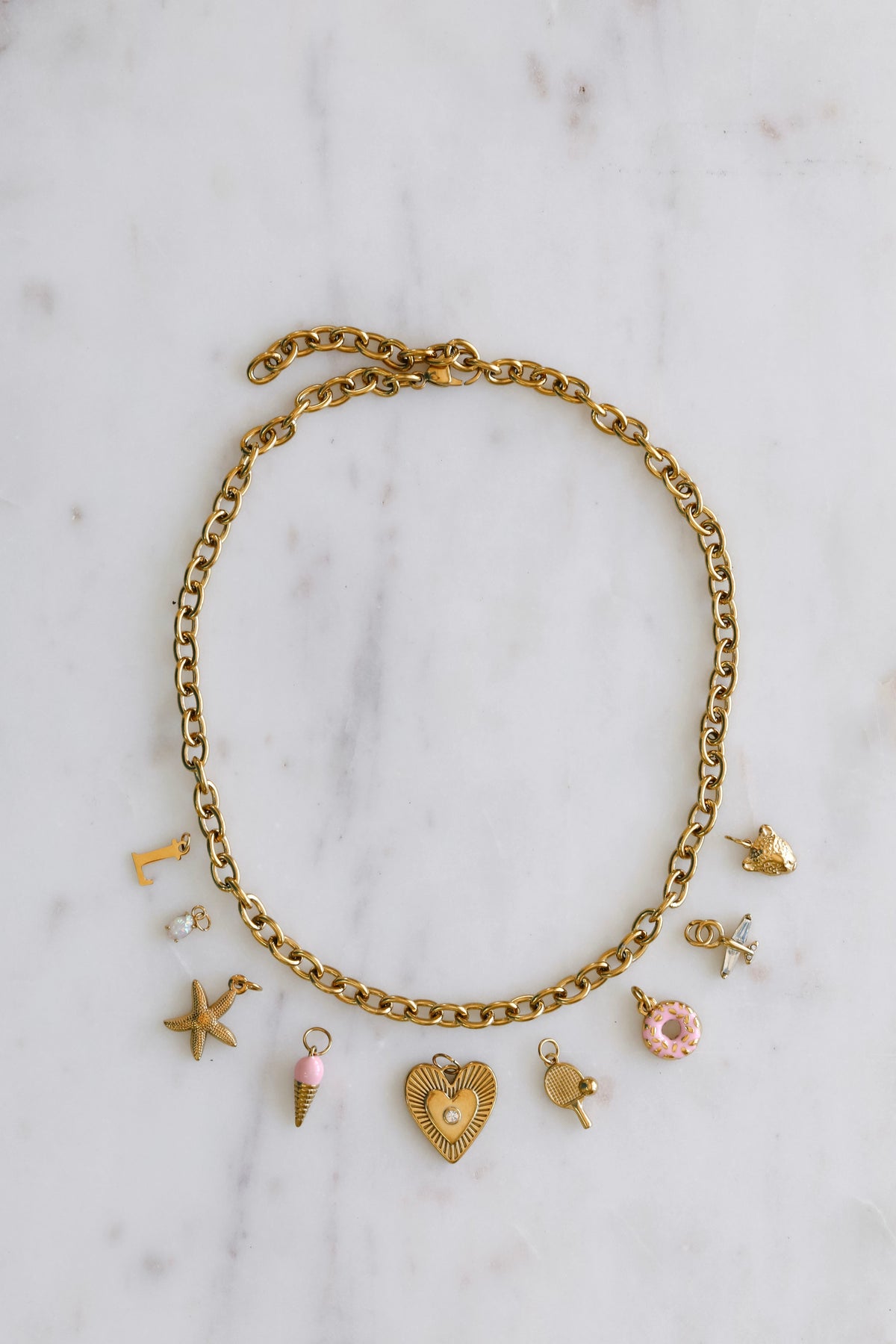 Gold charm bracelet with various charms on a light background