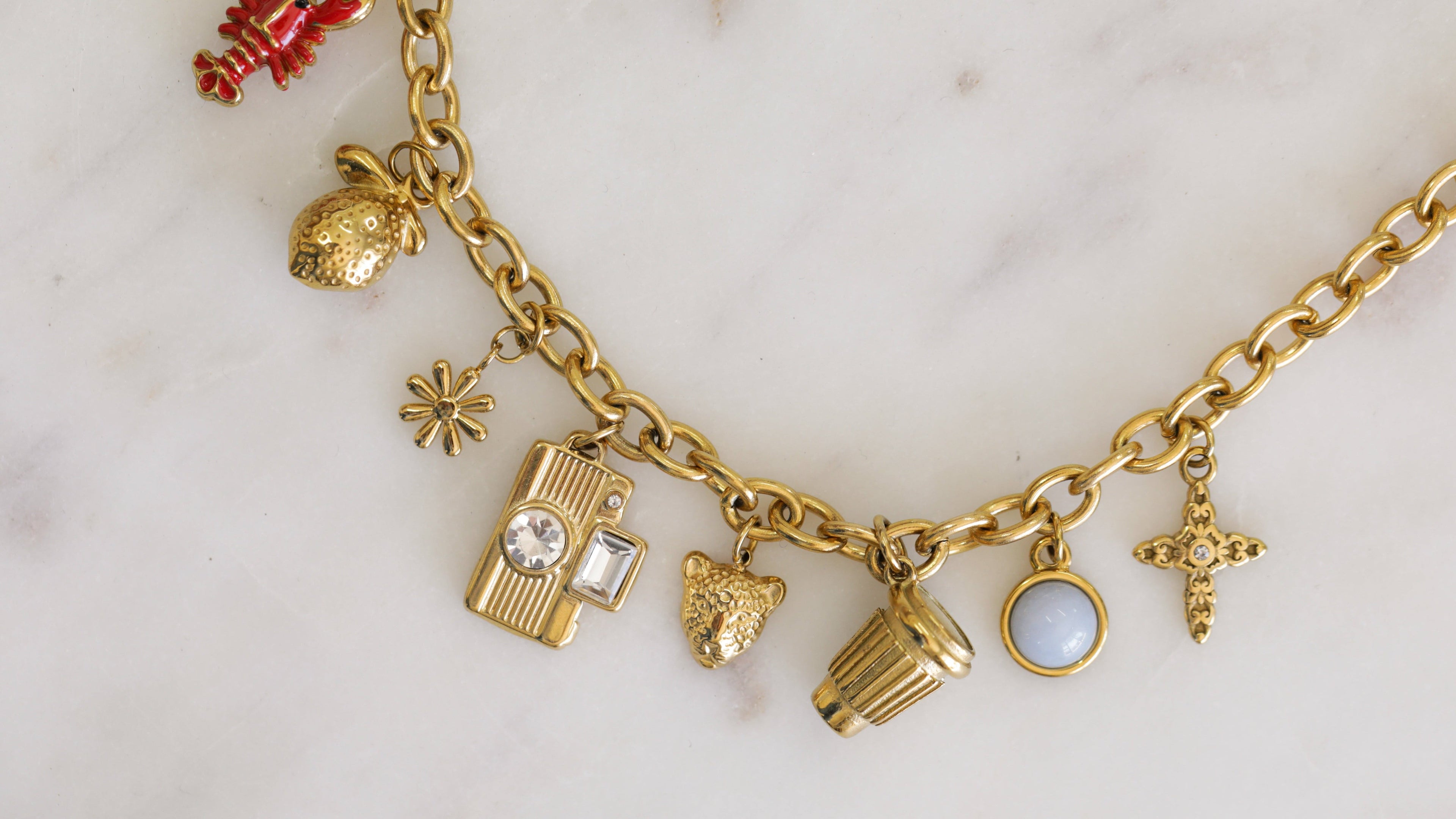 Gold charm bracelet with various charms on a light background